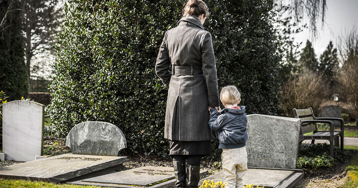 Mother and child standing next to a grave